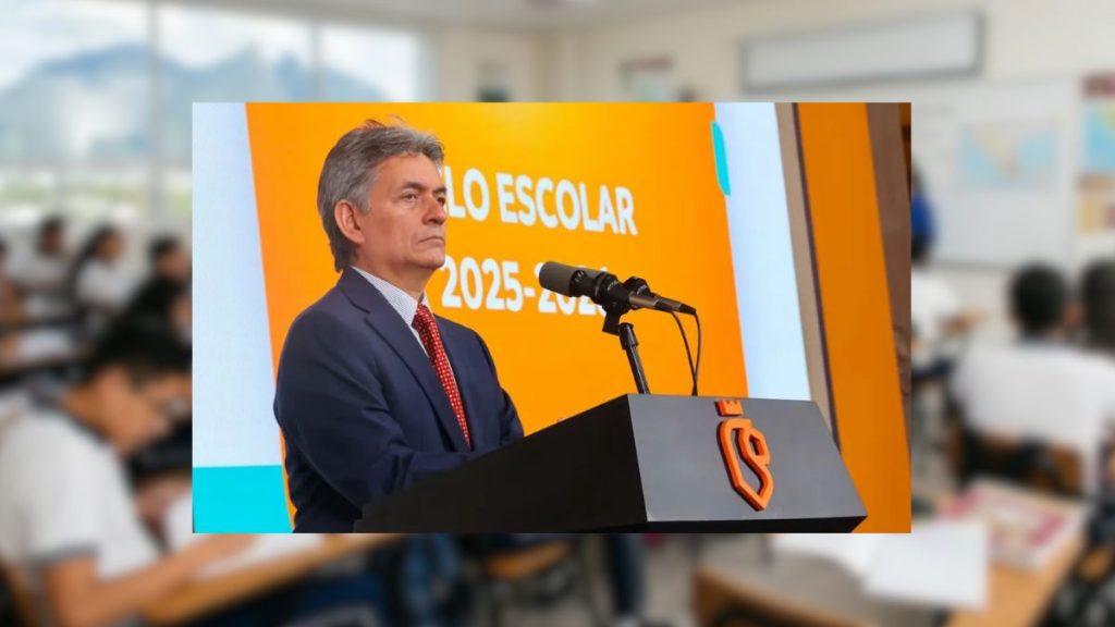 Man in a Dark Suit and Red Tie Speaks at a Podium with a Microphone, Orange Backdrop Behind Him at a Formal Event.] , - Salud Regia