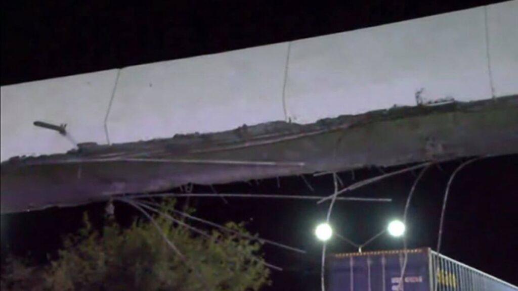 Puente-peatonal-constitución-tótems-naranjas-samuel-garcía - Salud Regia Nighttime View of a Severely Damaged Overpass with Broken Concrete, Exposed Cables, and Debris in the Scene. - Salud Regia